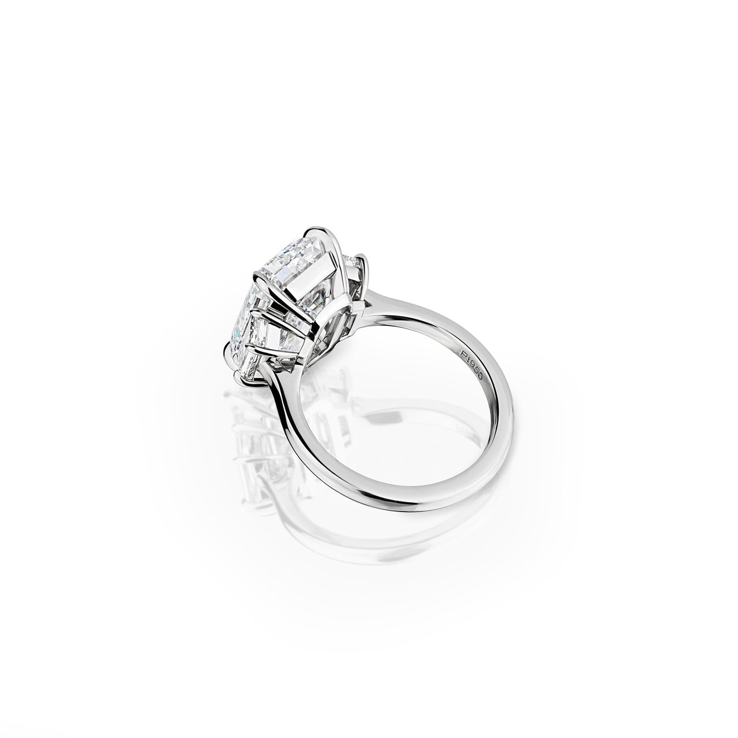 GIA-certified emerald and trapezoid cut three stone diamond ring, featuring a striking 7.57 carat center stone and 1.01 carats in side stones, set in platinum. Available for custom orders to suit any style preference.