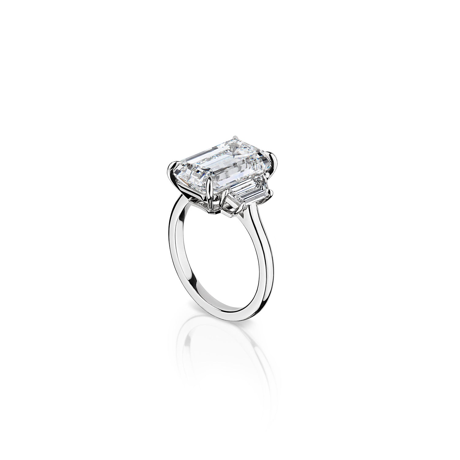 Exquisite three stone diamond ring with 1.01 carat trapezoid cut side stones of G-H color and VVS2 clarity, complementing a large emerald center stone, set in platinum. A perfect blend of luxury and craftsmanship.